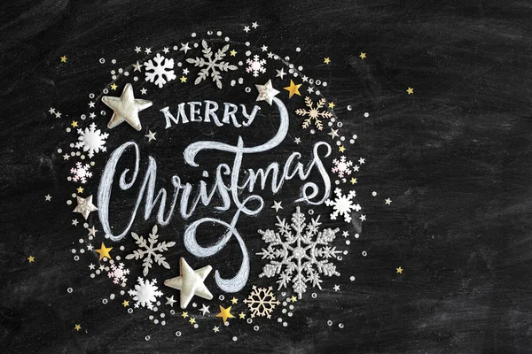 コンフェッティとクリスマスの装飾が施された黒い黒板にチョークで書かれたメリークリスマス 上から見た平らなレイアウト ストック画像