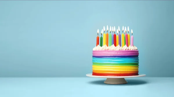 パーティーのためのカラフルな虹の誕生日のろうそくとカラフルな虹の誕生日ケーキ コピースペース付きの青の背景 — ストック写真