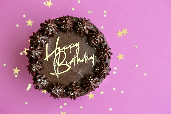 巧克力生日蛋糕 上面有金色的生日信 背景是粉色的 俯瞰着整个世界 — 图库照片