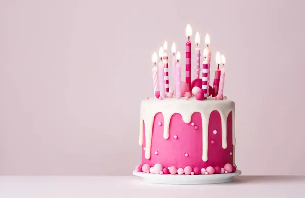 Pink celebration birthday cake with drip icing and pink birthday candles