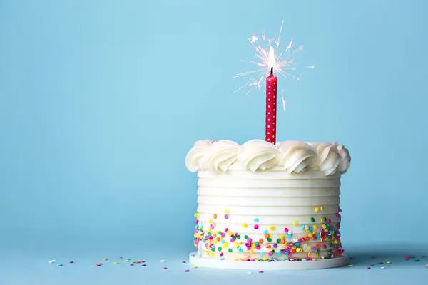 生日蛋糕 有五颜六色的洒水和一根红色生日蜡烛 衬托着浅蓝色的背景 — 图库照片