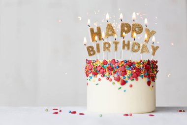 Altın mumlar ve kalp şeklinde serpiştirilmiş mutlu yıllar pastası.