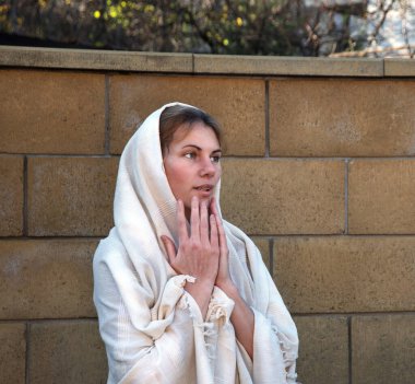 Mütevazı kutsal lütuf genç azize imanlı gelin eline hürmetle dua et Yüce İsa 'dan yardım iste eski beyaz Arap elbise örtüsü. Neşeli yahudi bakire Mary korkuyla yüzleşiyor.