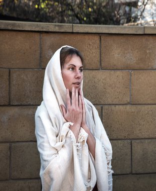 Mütevazı kutsal lütuf genç azize imanlı gelin eline hürmetle dua et Yüce İsa 'dan yardım iste eski beyaz Arap elbise örtüsü. Neşeli yahudi bakire Mary korkuyla yüzleşiyor.