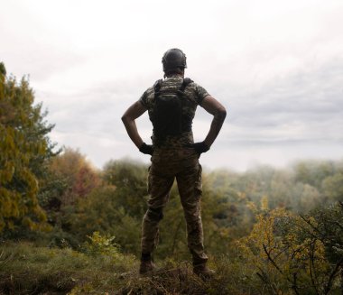 Yalnız, yorgun, genç, ABD 'li, NATO' lu erkek, dinleniyor. Kalça bel, bak. Tehlike ormanı, ağaç ışığı, beyaz gökyüzü mesaj sahası. Yalnız üzgün üzgün üzgün üzgün üzgün hisset. Kayıp veteriner kahraman tanrı inancı kavramı.