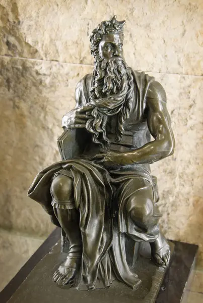 Bronze replica of famous world statuette - figurine Moshe by roman artist Michaelangelo Buonarroti, located in San Pietro in Vincoli basilica, Italy. View close-up with space for text on stone wall