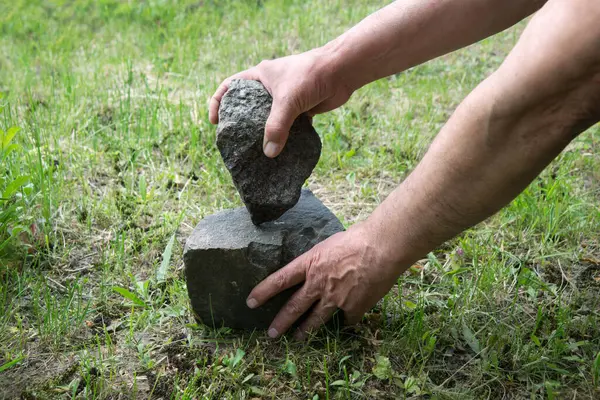 stock image Habilis erectus nude boy sculptor palm made art artifact skill heavy hard basalt rock cobble dirt grass ground soil text space. Past era retro archaic age epoch primal nomad survive active make symbol