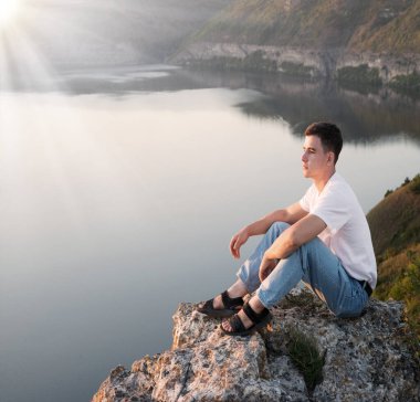 Kırsal, yalnız, üzgün, genç bir adam Tanrı 'ya ibadet etmez. İsa Mesih' in inancı, yaşama güvenir. Neşeli, neşeli, inançlı, duacı çocuk sakin, vahşi park ağacı göleti vadisi manzarasına bak.