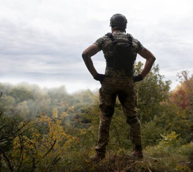 Yalnız, yorgun, genç, ABD 'li, NATO' lu erkek, dinleniyor. Kalça bel, bak. Tehlike ormanı, ağaç ışığı, beyaz gökyüzü mesaj sahası. Yalnız üzgün üzgün üzgün üzgün üzgün hisset. Kayıp veteriner kahraman tanrı inancı kavramı.