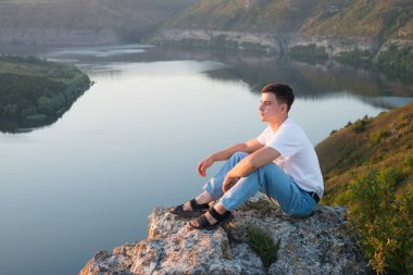 Kırsal, yalnız, üzgün, genç bir adam Tanrı 'ya ibadet etmez. İsa Mesih' in inancı, yaşama güvenir. Neşeli, neşeli, inançlı, duacı çocuk sakin, vahşi park ağacı göleti vadisi manzarasına bak.