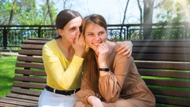 İki güzel yetişkin bayan, yaz kenti şehir merkezindeki ağaçlık alanda yalan söylüyor. Gençlik ilişkisi yalancısı. Bak, neşeli neşe şoku. Gülümse.