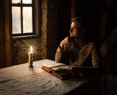 Genç yalnız başına umut dolu insan yüzü kutsal ilahi İsa koltuğu bak ve kutsal sayfayı aç. Antik İsrail 'in üzgün, yalnız, erkek, erkek, siyah, alev alev, aydınlık, kilise odası, uzay.