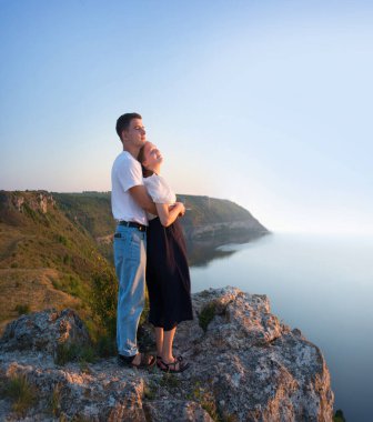 2 genç taşralı erkek, neşe dolu bir eğlence istirahatı için güneşli bir ortama bakıyor. Mutlu gülümseme bayan yürüyüşçü el ele tutuşun barış okyanus yürüyüşü kaya tepesi sahnesine tırmanın
