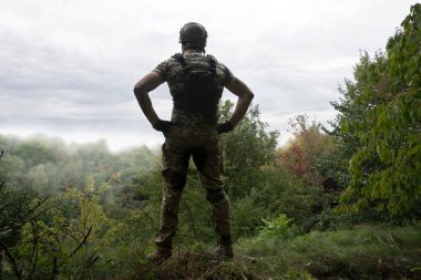 Yalnız, yorgun, genç, ABD 'li, NATO' lu erkek, dinleniyor. Kalça bel, bak. Tehlike ormanı, ağaç ışığı, beyaz gökyüzü mesaj sahası. Yalnız üzgün üzgün üzgün üzgün üzgün hisset. Kayıp veteriner kahraman tanrı inancı kavramı.