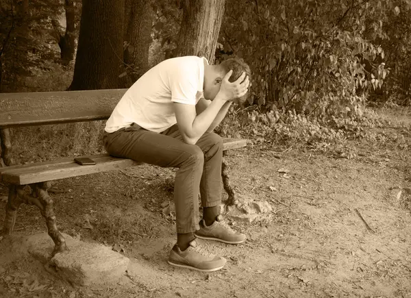 Genç, yorgun, ruhsal çöküntüye uğramış kederli çocuk, suçlu çocuk, şehrin kırsal kesiminde, kırsal kesiminde, çalının derinliklerinde bir mesaj alanı arıyor. Kayıp aşk çatık kaşlı adam koltuğu dinlenme eski antika sandalye bekle Tanrı 'ya inan