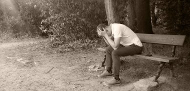 Genç, yorgun, ruhsal çöküntüye uğramış kederli çocuk, suçlu çocuk, şehrin kırsal kesiminde, kırsal kesiminde, çalının derinliklerinde bir mesaj alanı arıyor. Kayıp aşk çatık kaşlı adam koltuğu dinlenme eski antika sandalye bekle Tanrı 'ya inan