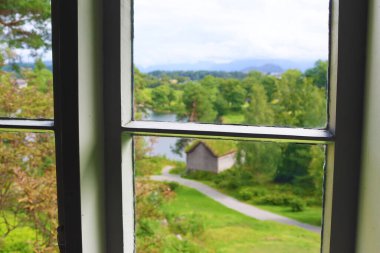 Alesund, Norveç - 01 Ağustos 2024: Pencereden bakın. Sunnmore Müzesi, çimenli çatıları olan 56 eski evi olan bir açık hava müzesi.