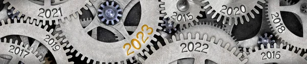 Photo of tooth wheel mechanism with numbers 2023, 2022, 2011 imprinted on metal surface. New Year concept.