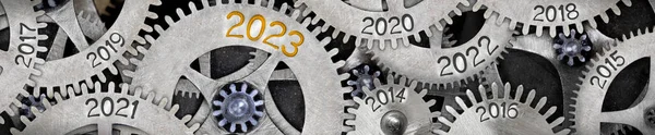 Photo of tooth wheel mechanism with numbers 2023, 2022, 2021 imprinted on metal surface. New Year concept.