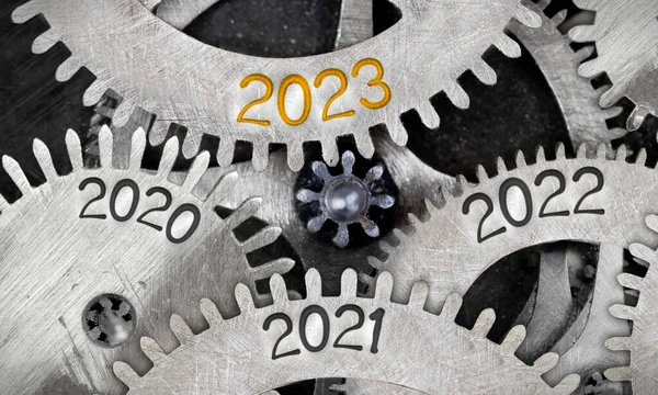 Photo of tooth wheel mechanism with numbers 2023, 2022, 2011 imprinted on metal surface. New Year concept.