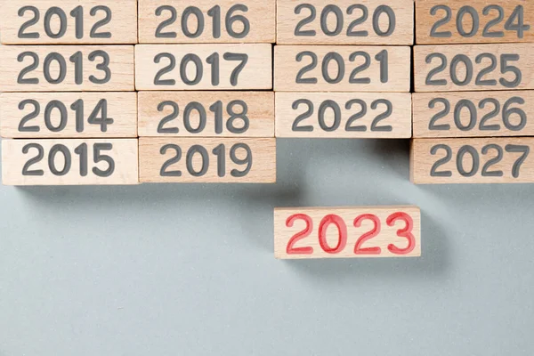 Photo of wooden blocks with gray numbers and red number 2023 imprinted on wooden surface. New Year concept.