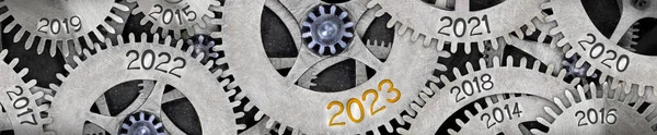Photo of tooth wheel mechanism with numbers 2023, 2022, 2021... imprinted on metal surface. New Year concept.