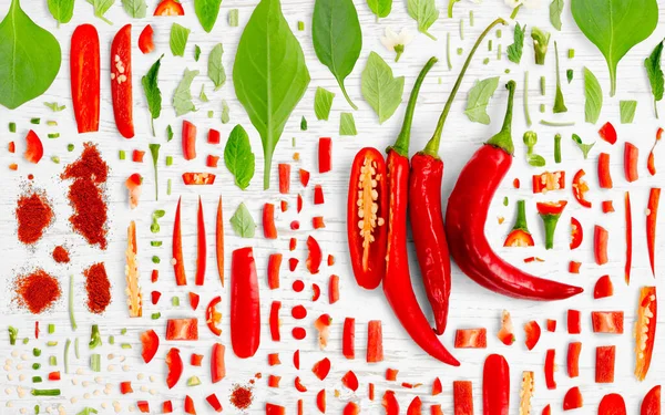 木の背景に赤唐辛子の野菜片 スライス 葉で作られた抽象的な背景 — ストック写真