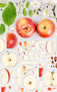 Kırmızı Elma meyve parçaları, dilimler ve gri arkaplanda izole edilmiş yapraklardan oluşan soyut bir arkaplan.