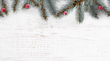 Beyaz ahşap arka planda Noel süslemeleri ve dalları.