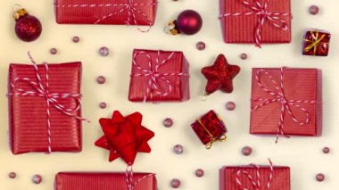 Kırmızı Noel süslemeleri ve parlak arka planda hediyeler. Üst manzara, düz yatış, pürüzsüz döngü. Yüksek kalite 4k video.