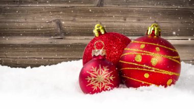 Kar yağışı altında kırmızı top grubunun karla kaplı olduğu bir hayat. Arka planda ahşap masa. Düşen kar etkisi. Noel, tatil ve kış konsepti. Yüksek kalite 4k video.