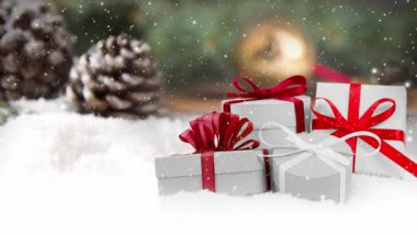 Karla kaplı yüzeyde hediye grubuyla hala hayat var. Arka planda çam kozalakları ve ladin dalları var. Düşen kar etkisi. Noel, tatil ve kış konsepti. Yüksek kalite 4k video.