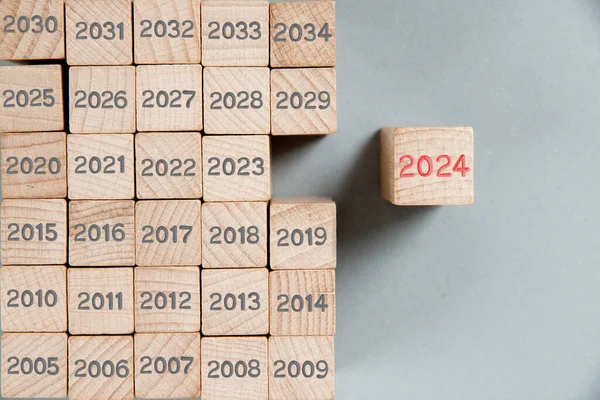 照片上的木块排经过数年的灰色数字 其中一个突出的红色数字2024印在木制表面 新年概念 免版税图库照片