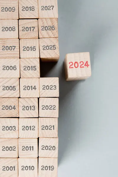 木製のブロック行の写真は 何年も経過した灰色の数で そのうちの1つは木製の表面に刻まれた赤い番号2024で際立っています 新年コンセプト ロイヤリティフリーのストック画像