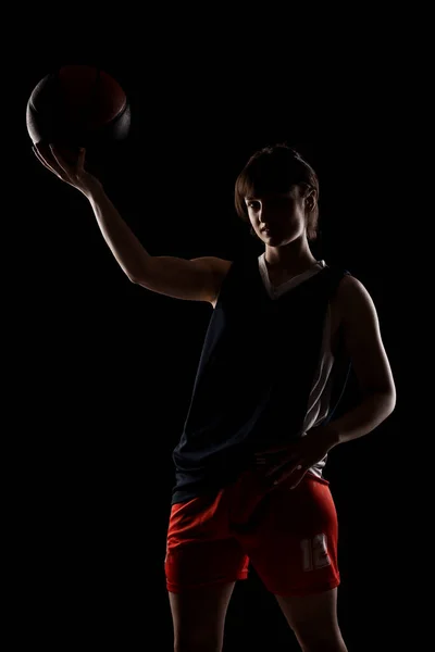 女篮球运动员 漂亮的女孩拿着球 背景为黑色的侧光半人半人物肖像 — 图库照片