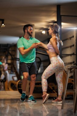 Birbirine aşık çiftler Bachata ve tango yapıyor. Kız ve erkek spor salonunda egzersiz yaparken eğleniyorlar..