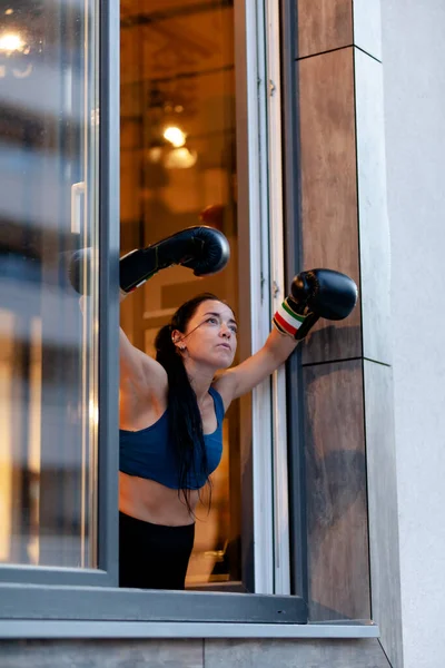 フィット女の子でボクシング手袋リラックスし 運動から休憩中に窓の外を見る — ストック写真
