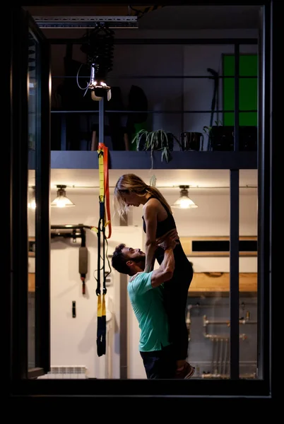 Couple in love. Boy and girl hugging in a fitness studio. View from outside the window frame.