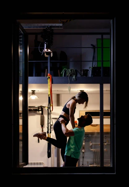 Couple in love. Boy and girl hugging in a fitness studio. View from outside the window frame.