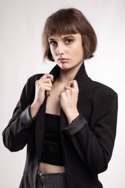 Kısa saçlı, iş kıyafeti giyen güzel bir kızın stüdyo portresi..