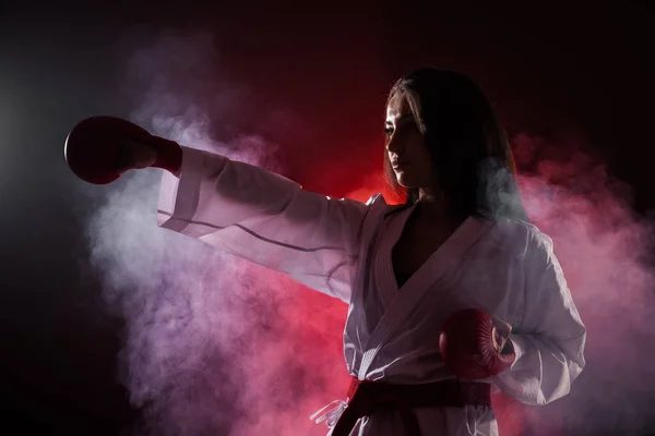 在红色雾气背景下练习空手道拳的女孩 — 图库照片