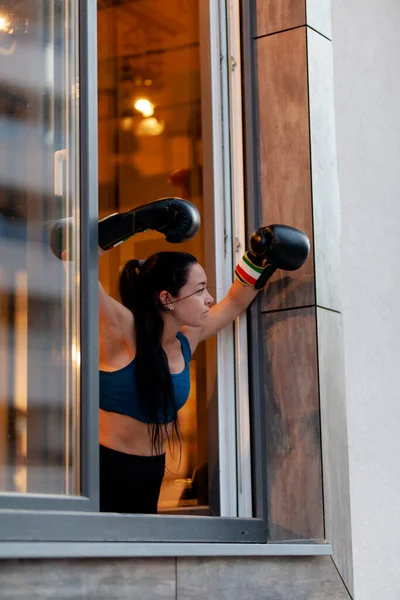 フィット女の子でボクシング手袋リラックスし 運動から休憩中に窓の外を見る — ストック写真