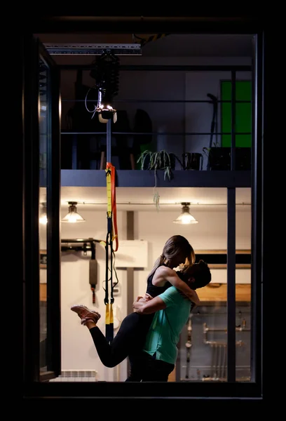 恋爱中的情侣男孩和女孩在健身室拥抱 从窗框外部看 — 图库照片