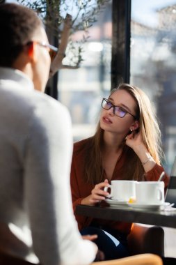 Friends in a restaurant talking smiling and drinking tea. Business colleagues having a meeting after work or during coffee break at a cafe bar.
