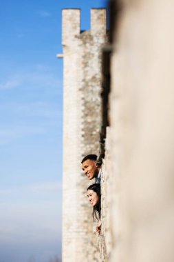 Eski bir kalenin duvarlarından manzaranın keyfini çıkaran çok ırklı bir çift. Aşık bir adam ve kadın.