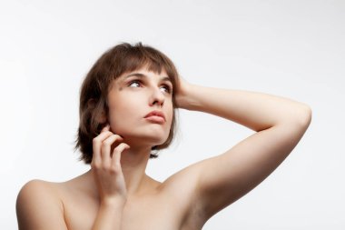 Güzel esmer bir kızın stüdyo portresi. Kısa saçlı. Beyaz arka planda izole bir şekilde yukarı bakıyor..