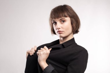 Kısa saçlı, iş kıyafeti giyen güzel bir kızın stüdyo portresi..