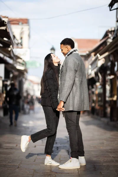 Multiracial couple posing on narrow streets in old part of the sity. Old turkish bazaar in Skopje, North Macedonia.