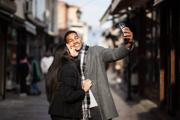 Multiracial couple posing on narrow streets in old part of the sity. Taking selfy photo with phone. Old turkish bazaar in Skopje, North Macedonia.