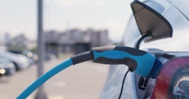 Elektrikli arabanın prizinden güç kablosunu çıkarmaya çalışan bir erkek..